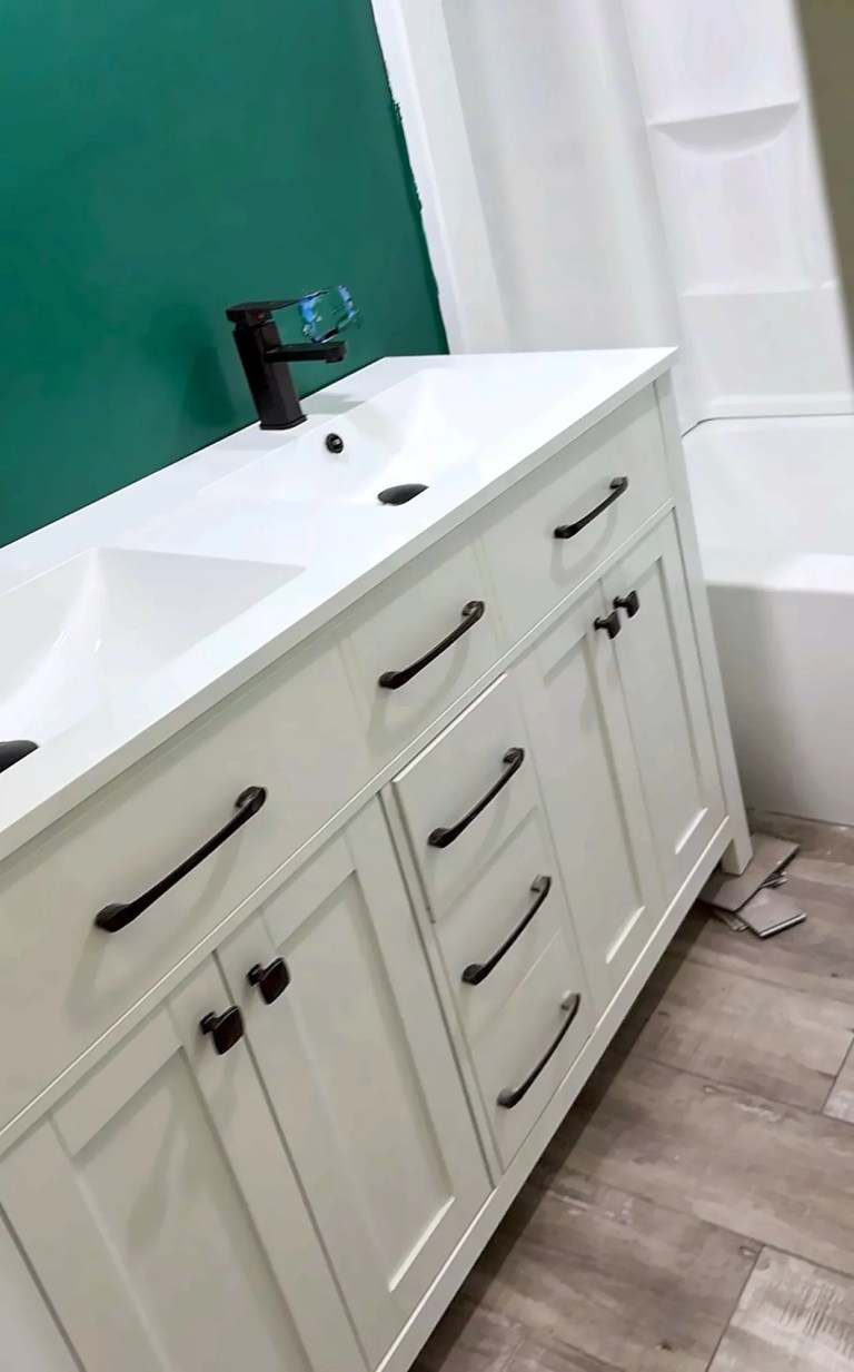Renovated bathroom with a white shaker vanity, matte black pulls and a deep emerald accent wall, part of a whole-home renovation by Dom's Workshop