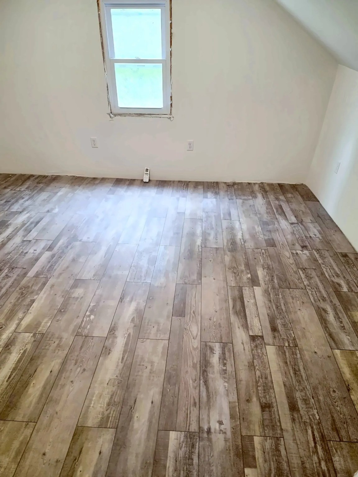 Attic converted into a bright finished room with a gable window, white walls and new wide-plank flooring, by Dom's Workshop